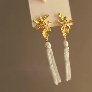Gros plan de boucles d'oreilles fleurs vintage avec perle et longs pompons