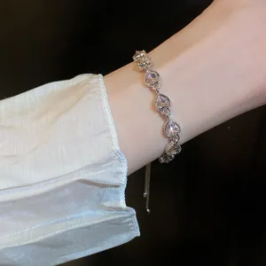 Close-up of silver-toned heart-shaped zircon bracelet on wrist with elegant sparkling detail.