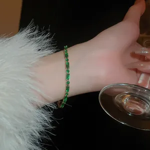 Close-up of luxury gold plated bracelet with emerald green zircons worn on a lady wrist