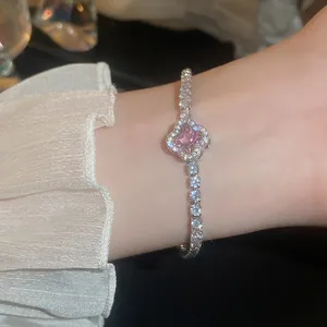 Close-up of a sparkling silver bracelet with a pink zircon stone on a woman's wrist.