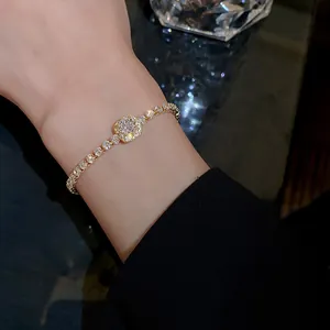 Elegant gold-plated bracelet with sparkling zircons shown as a close-up on a woman's wrist.