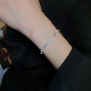Elegant gold-plated zircon tennis bracelet with sparkling stones on wrist detail view.