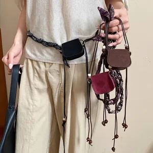 Close-up of retro fashion waist chain featuring miniature suede accessory bags.