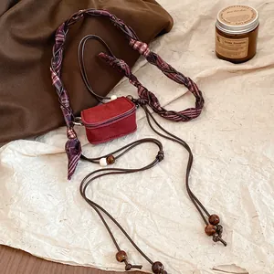 Close-up of a vintage red suede mini bag waist chain with braided cord and beads.