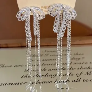 Dettaglio di orecchini a fiocco in argento con nappine e strass luccicanti