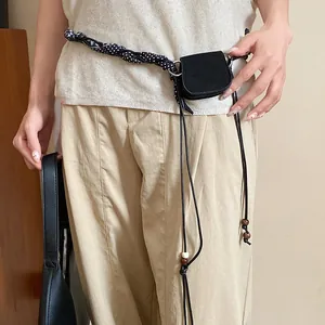 Close-up of a retro-style waist bag with a black and white polka-dot braided strap on pants