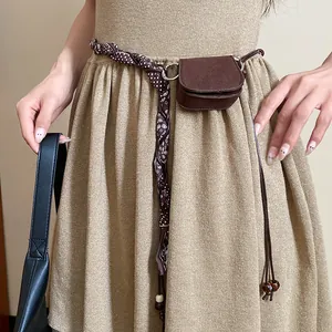 Detailed view of a retro brown mini pouch waist chain worn on a tan knit dress
