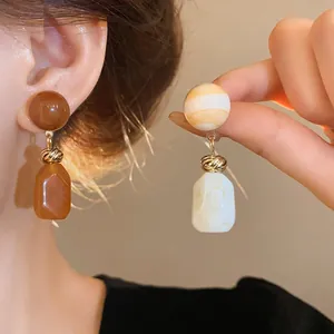 Detailed shot of retro Maillard style resin drop earrings on a model's ear