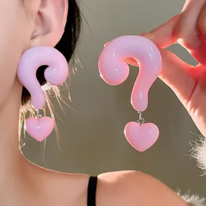 Close-up detail of oversized pink resin question mark earrings with cute heart pendants