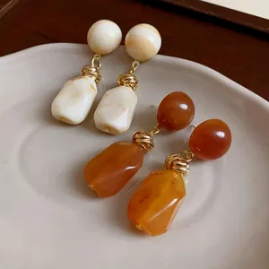 Macro view of vintage resin irregular drop earrings in marble white and warm amber colors