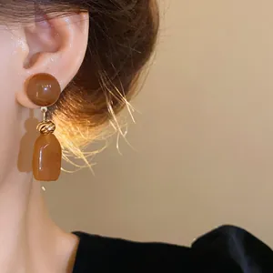 Detail view of vintage Maillard brown resin drop earrings featuring irregular shapes and gold accents.
