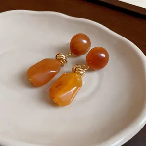 Macro view of Maillard style irregular amber resin earrings with golden metal details