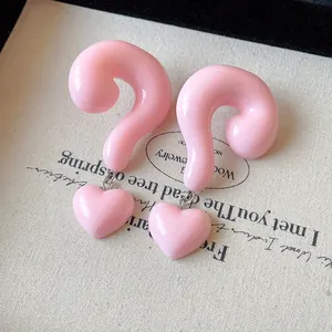 Close-up of pink resin earrings featuring question mark and heart pendants