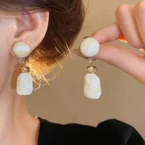 Detail shot of vintage Maillard resin earrings with marbled pendants and gold accents.