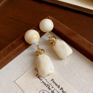 Close-up of vintage resin drop earrings with marble pattern and golden metal knots
