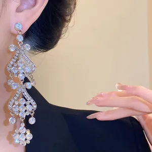 Close-up shot of elegant silver needle rhinestone tassel earrings worn on model's ear.