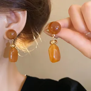 Detailed view of vintage Maillard amber irregular resin drop earrings worn on the ear