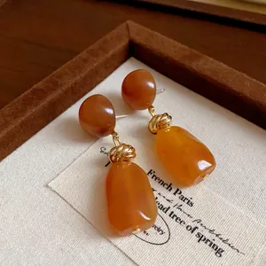 Close-up of vintage irregular amber resin earrings with elegant golden knot details