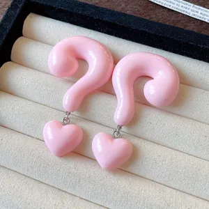 Close-up of pink resin question mark heart drop earrings in a jewelry display tray