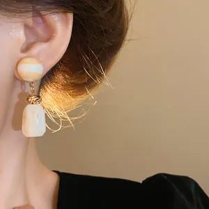 Elegant retro Maillard style irregular resin drop earrings shown on an ear model detail