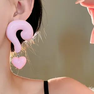 Close-up of pink resin earrings featuring a unique question mark and heart shape design on model