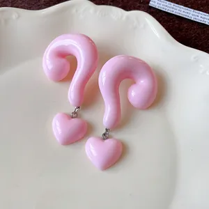 Detailed macro view of pink resin question mark stud earrings with dangling heart charms
