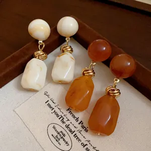 Detailed view of vintage irregular resin drop earrings in cream and amber brown tones