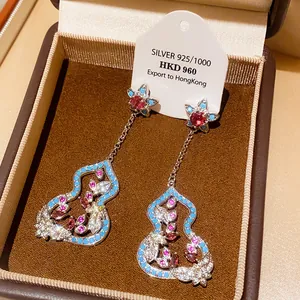 Detailed view of silver gourd-shaped drop earrings with colorful gemstones in a gift box