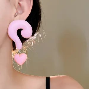 Close-up detail of oversized pink resin question mark earrings with heart charms on model