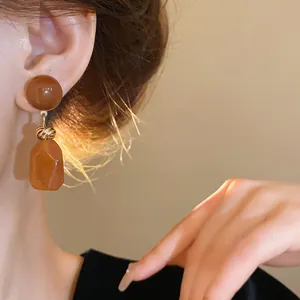 Close-up view of vintage Maillard style irregular resin earrings worn on a model's ear