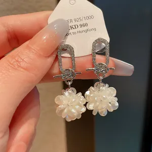 Elegante silberne Ohrringe mit Zirkonia und weißen Blumenanhängern im Detail