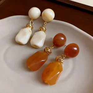 Detailed close-up of irregular resin earrings in Maillard tones with gold accents