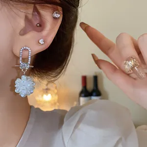 Nahaufnahme eleganter silberner Diamantohrringe mit einem weißen Blumenbüschel-Anhänger