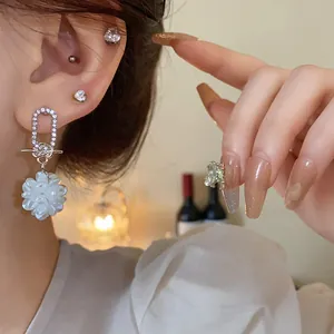 Nahaufnahme von silbernen Ohrringen mit glitzernden Strasssteinen und weißen Blumen
