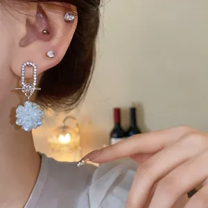 Nahaufnahme der funkelnden Silberohrringe mit weißer Perlenblume und Diamantbesatz