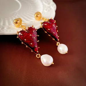Macro detail view of Baroque style red heart earrings featuring white baroque pearls