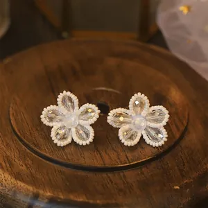 Elegant retro flower stud earrings with white beads and clear crystals on wood base