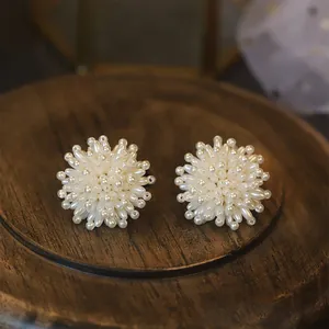 Vintage creamy pearl cluster flower stud earrings presented on a dark rustic wooden stand