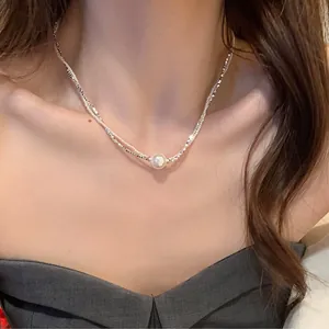 Detail van dubbellaagse zilveren ketting met elegante parel gedragen door een model