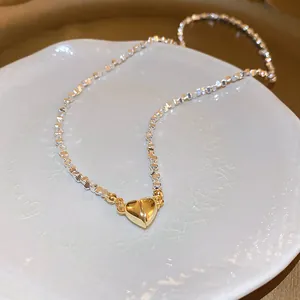 Detailopname van een zilveren kralenketting met een gouden magnetische harthanger