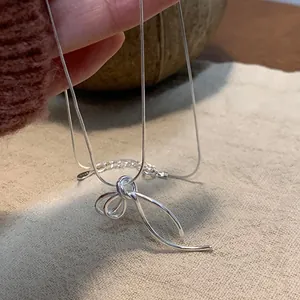 Detailopname van een zilveren ketting met strikhanger en een verfijnde slangenketting