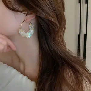 Detailed view of model wearing vintage iridescent flower hoop earrings with silver pins