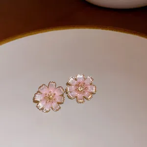 Close-up detail of pink cherry blossom earrings with golden edges and sparkly finish