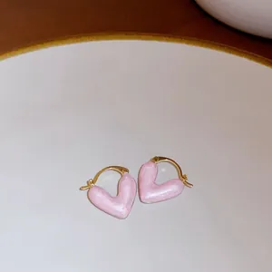 Detail view of pearlescent pink heart-shaped hoop earrings on a white ceramic plate