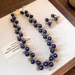 Close-up of vintage blue resin bead necklace and earring set with golden textures.