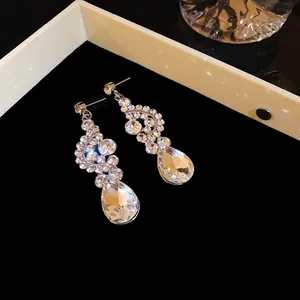Primo piano di eleganti orecchini a pendente con strass a ventaglio e goccia su nero.