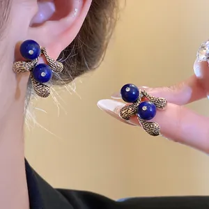 Close-up of vintage resin earrings with blue spheres and textured gold finish