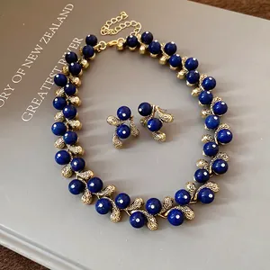 Vintage style blue resin bead necklace and earrings set on a grey book background
