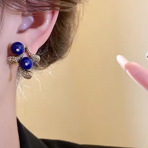 Close-up of vintage resin stud earrings with blue beads and gold leaf texture