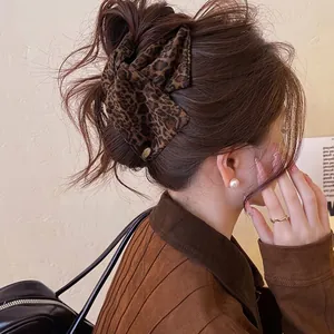 Elegant leopard print satin triangle hair claw clip shown in a stylish women's bun hairstyle
